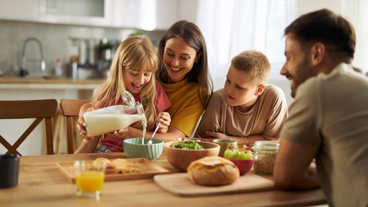 Happy,Little,Girl,Pouring,Milk,Into,Bowl,Of,Cereals,While