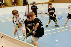 Children boys schoolchildren playing floorball (floor hockey) match in school gym hall with plastic hockey sticks