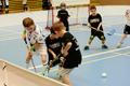 Children boys schoolchildren playing floorball (floor hockey) match in school gym hall with plastic hockey sticks