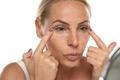 Middle,Aged,Senior,Woman,Applyes,Concealer,Under,Her,Eyes,On