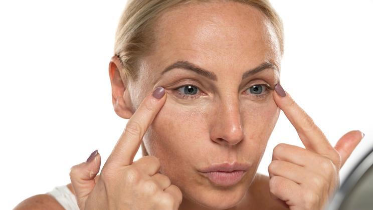 Middle,Aged,Senior,Woman,Applyes,Concealer,Under,Her,Eyes,On