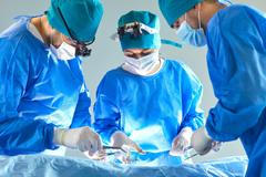 Team,Of,Professional,Doctors,Surgeons,Wearing,Blue,Medical,Uniform,Performing