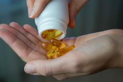 Close-up,Of,A,Woman,Pouring,Vitamin,D,Or,Omega-3,Into