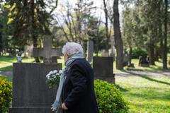 Elderly,Widow,Bringing,Flowers,To,A,Grave,At,Cemetery.
