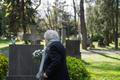 Elderly,Widow,Bringing,Flowers,To,A,Grave,At,Cemetery.