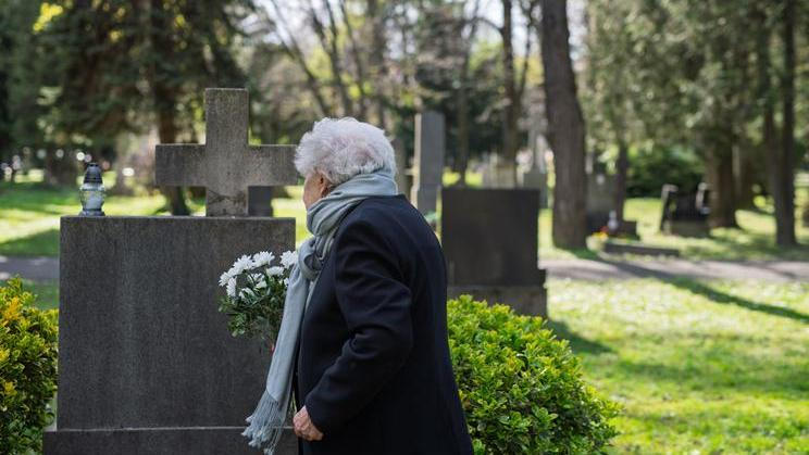 Elderly,Widow,Bringing,Flowers,To,A,Grave,At,Cemetery.