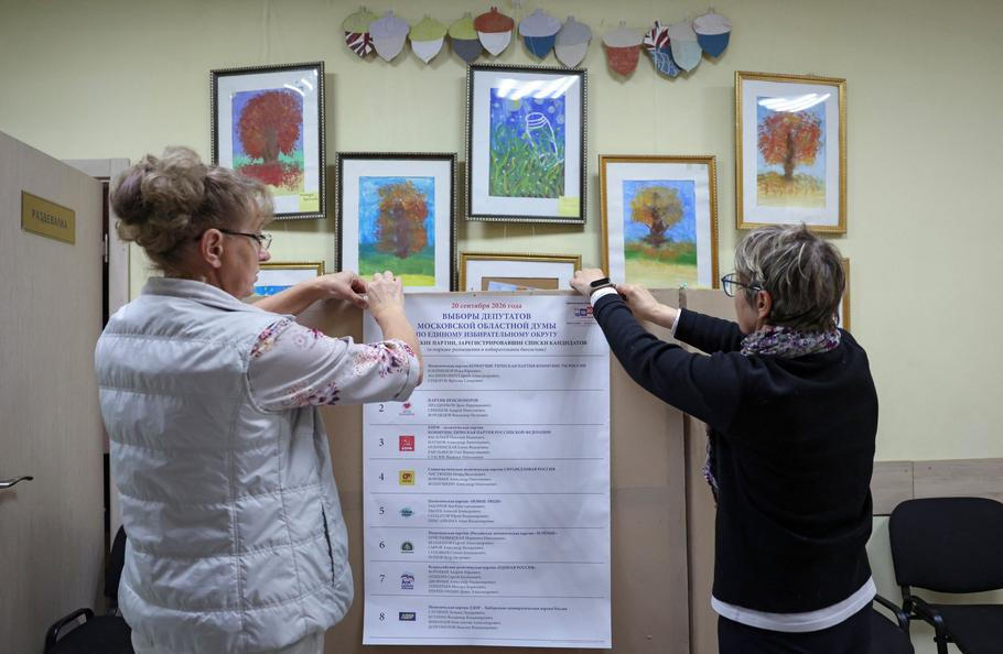 Election officials hang a list of political parties at a polling station in Podolsk