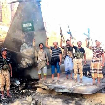 Houthi fighters stand in front of what they say is a downed Saudi jet, at a location given as Yemen