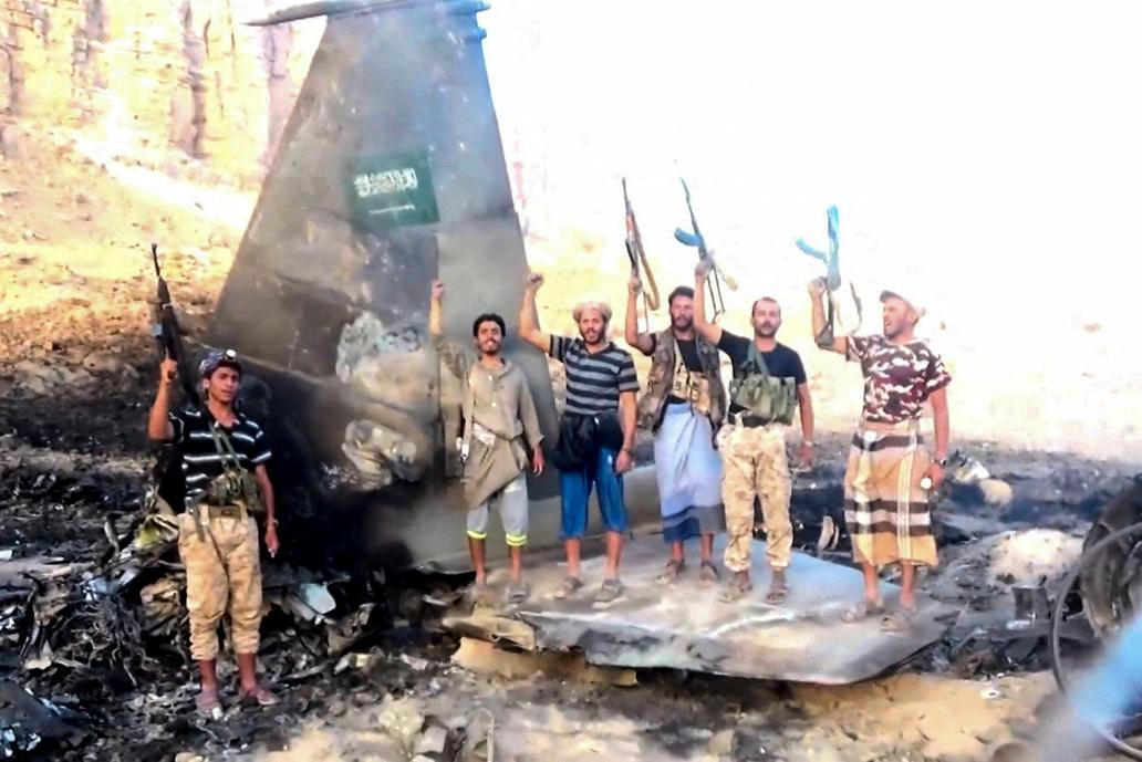 Houthi fighters stand in front of what they say is a downed Saudi jet, at a location given as Yemen