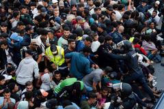 Police escort migrants from Benitez Beach to be relocated to the camp set up at the port of Ceuta