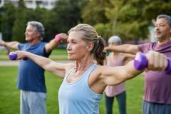 Elderly,People,Lifting,Small,Weights,At,Park.,Focused,Senior,Woman