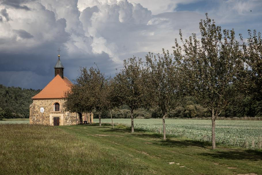 Dnes je louka u Berounky odlehlé místo, dřív tudy ale vedla zemská cesta, po níž proudili lidé. U kostela býval i ovocný sad, který Jiráskovi doufají opět obnovit.