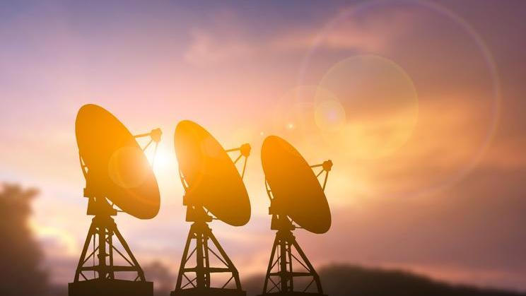 Three,Large,Satellite,Radar,Dishes,Standing,In,A,Row,,Silhouetted