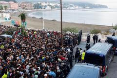 Police escort migrants from Benitez Beach to be relocated to the camp set up at the port of Ceuta