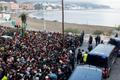 Police escort migrants from Benitez Beach to be relocated to the camp set up at the port of Ceuta