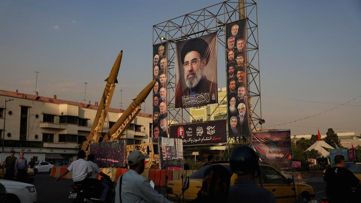 Iranian missiles are displayed next to a banner with a picture of Iran's Supreme Leader, Mojtaba Khamenei, on a street in Tehran