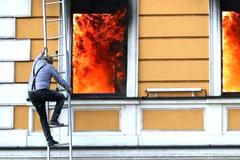A combination picture shows a man climbing out of a window to escape from burning building, in Kyiv
