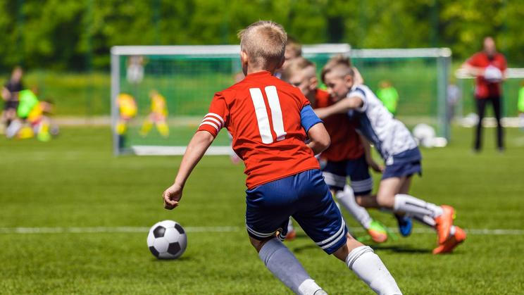 Football Soccer Match for Children. Kids Playing Soccer Game Tournament. Boys Running and Kicking Football. Youth Soccer Coach in the Background