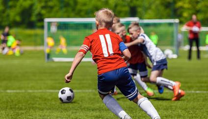 Football Soccer Match for Children. Kids Playing Soccer Game Tournament. Boys Running and Kicking Football. Youth Soccer Coach in the Background