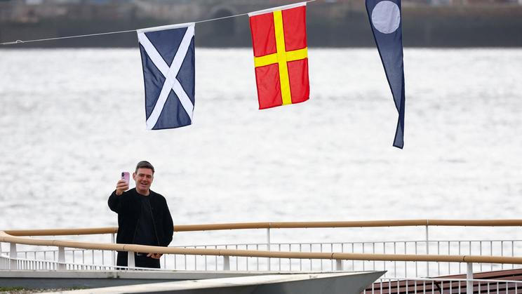 Britský ministerský předseda Andy Burnham fotící se s vlajkami zemí Spojeného království.