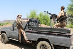 Government soldiers ride military pick-up vehicle on road leading to frontline in Taiz