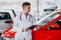 ["Car doctor with stethoscope in a car showroom"]