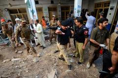 Police officers and military personnel gather as they're surveying the site of a school roof collapse at a hospital morgue in Peshawar